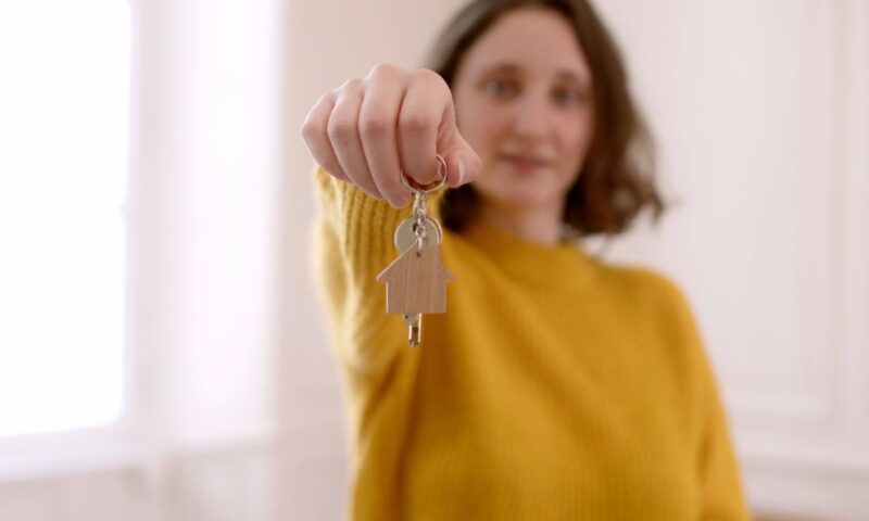 prikaz devojke u žutoj haljini koja drži ključeve od stana u ruci, fokus na ključevima