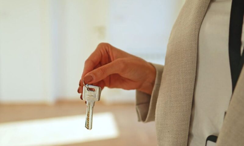 osoba drži ključeve od stana u ruci, u pozadini prazan stan